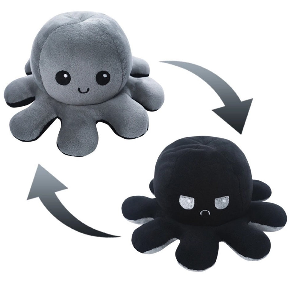 une peluche en forme d'octopus réversible grise et noire qui exprime deux émotions différentes : d'un côté, l'expression heureuse et joyeuse puis quand on le retourne, une expression boudeuse.