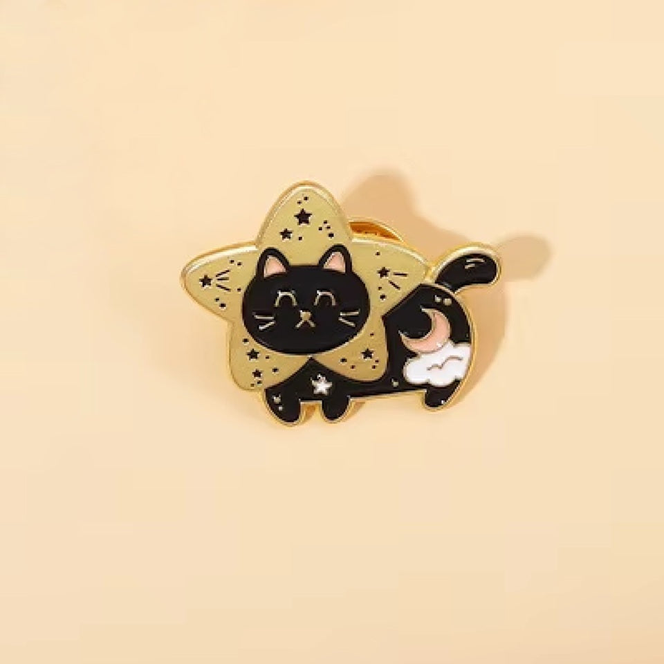 un pin's doré en forme d'un chat noir bien dodu et tout mignon dans la fourrure est ornée d'un croissant de lune et d'un nuage. Il a la tête dans une grande étoile dorée.