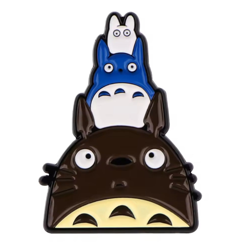 un pin's inspiré de Totoro et de ses amis. Sur la tête du gros Totoro se trouve le chibi bleu puis le chibi blanc, empilé les uns sur les autres