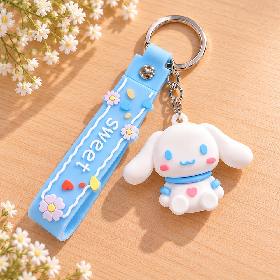 Porte-clés kawaii Cinnamoroll Sanrio posé à plat sur une jolie table en bois clair, entouré de délicates petites fleurs blanches. Cet adorable porte-clés représente Cinnamoroll, un petit chien blanc aux longues oreilles, aux joues roses et aux détails bleu pastel, accompagné d'une dragonne bleue décorée de fleurs, de cœurs colorés et de l'inscription « Sweet ». Un accessoire kawaii mignon et original, parfait pour personnaliser ses clés, son sac à main ou son sac à dos. Une adorable idée cadeau pour les amo