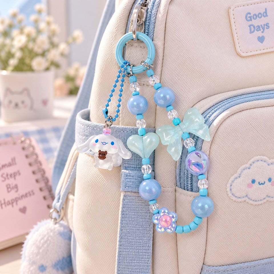 Porte-clés Cinnamoroll bleu en perles, décoré de nœuds, cœurs et fleur, accroché à un sac à dos beige et bleu au style kawaii.