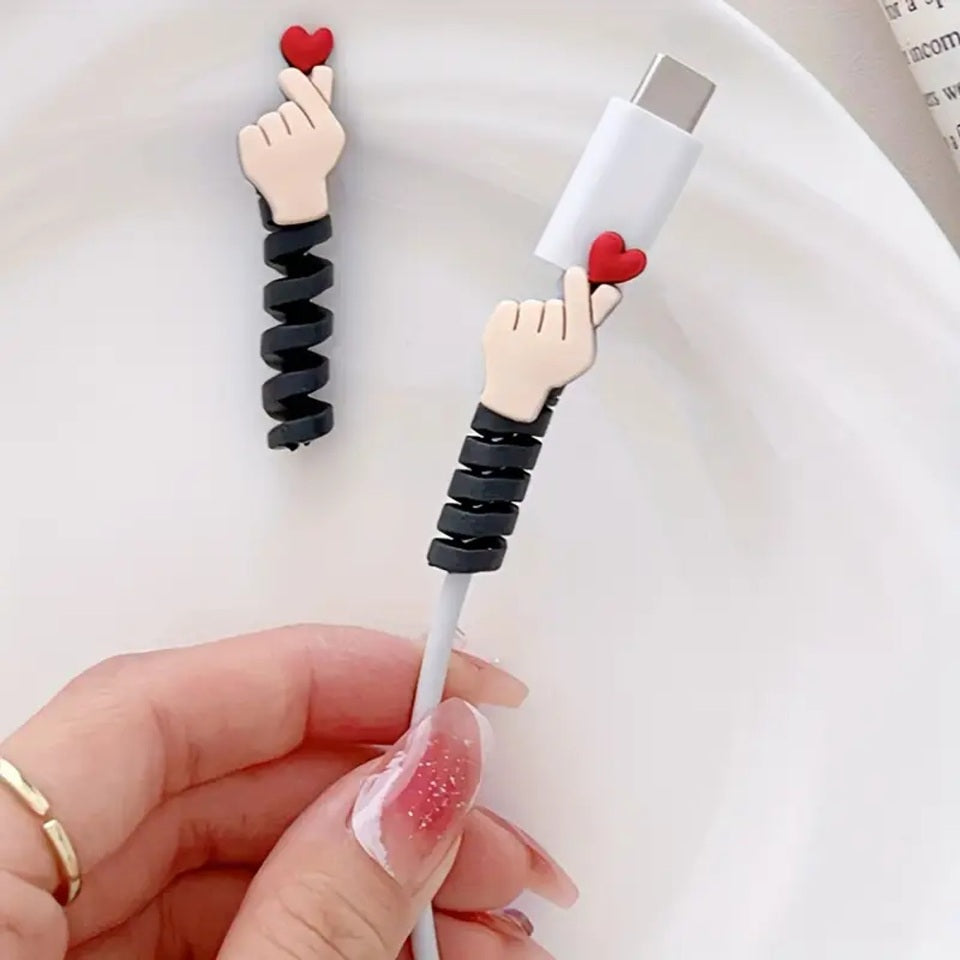 un protège câble en forme de mains qui forment un cœur, le finger heart coréen accompagné d'un joli cœur rouge. Idéal pour protéger et allonger la durée de vie de vos câbles