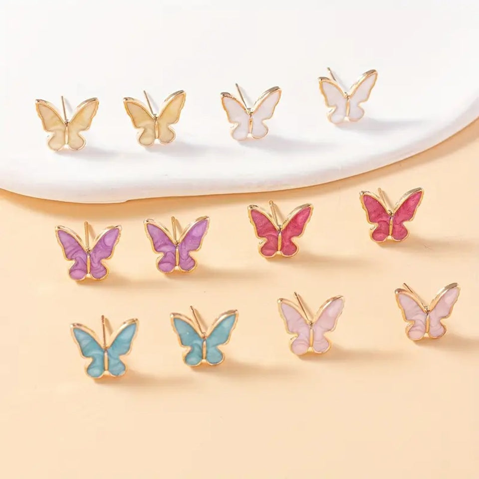 une paire de puces d'oreilles minimaliste en forme de papillons colorés et dorées : aune, blanc, violet, bleu, rose et fuschia