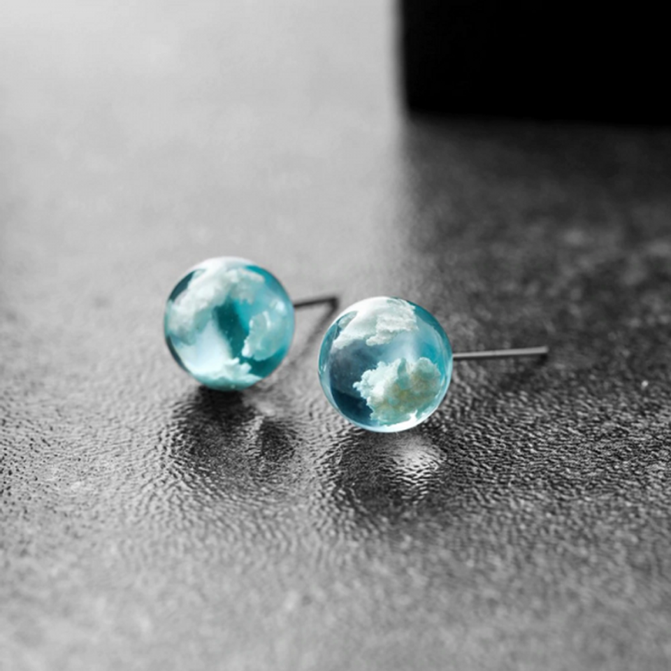 des boucles d'oreilles rondes en verre transparent et bleu. A l'intérieur, on peut voir comme des nuages blancs. On dirait que l'on a capturé un bout de ciel.