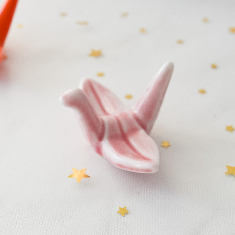 des repose baguettes en forme de grue japonaise colorée : rose, orange, bleu et vert. En céramique, elles sont résistantes et durables et ajoutent une touche authentique du Japon et d'élégance sur votre table.