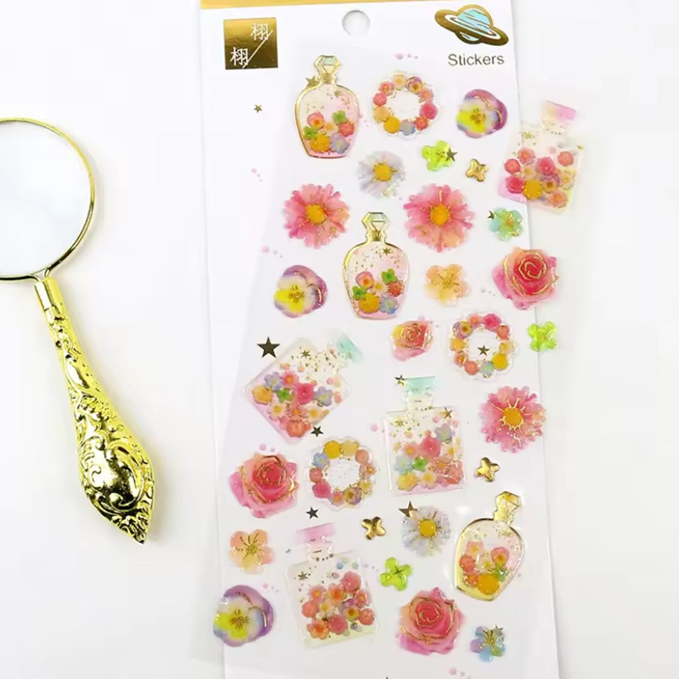 Une jolie planche de stickers en forme de bouteilles de parfum colorées et fleuries. Dans les tons roses, jaunes, bleus et verts, on dirait un jardin parfumé.