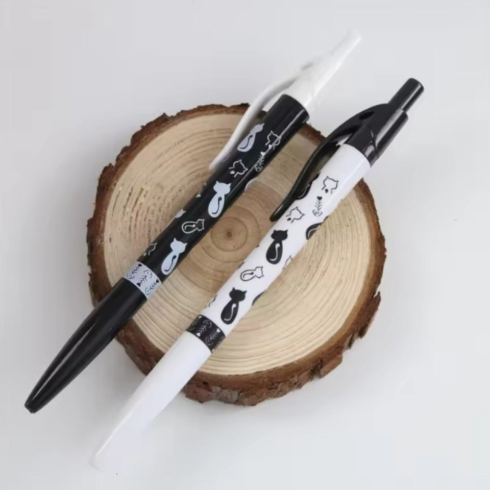 un stylo noir ou blanc orné de motif de chat noir et de chat blanc ainsi que d'arêtes de poisson. Le design est original et très mignon.