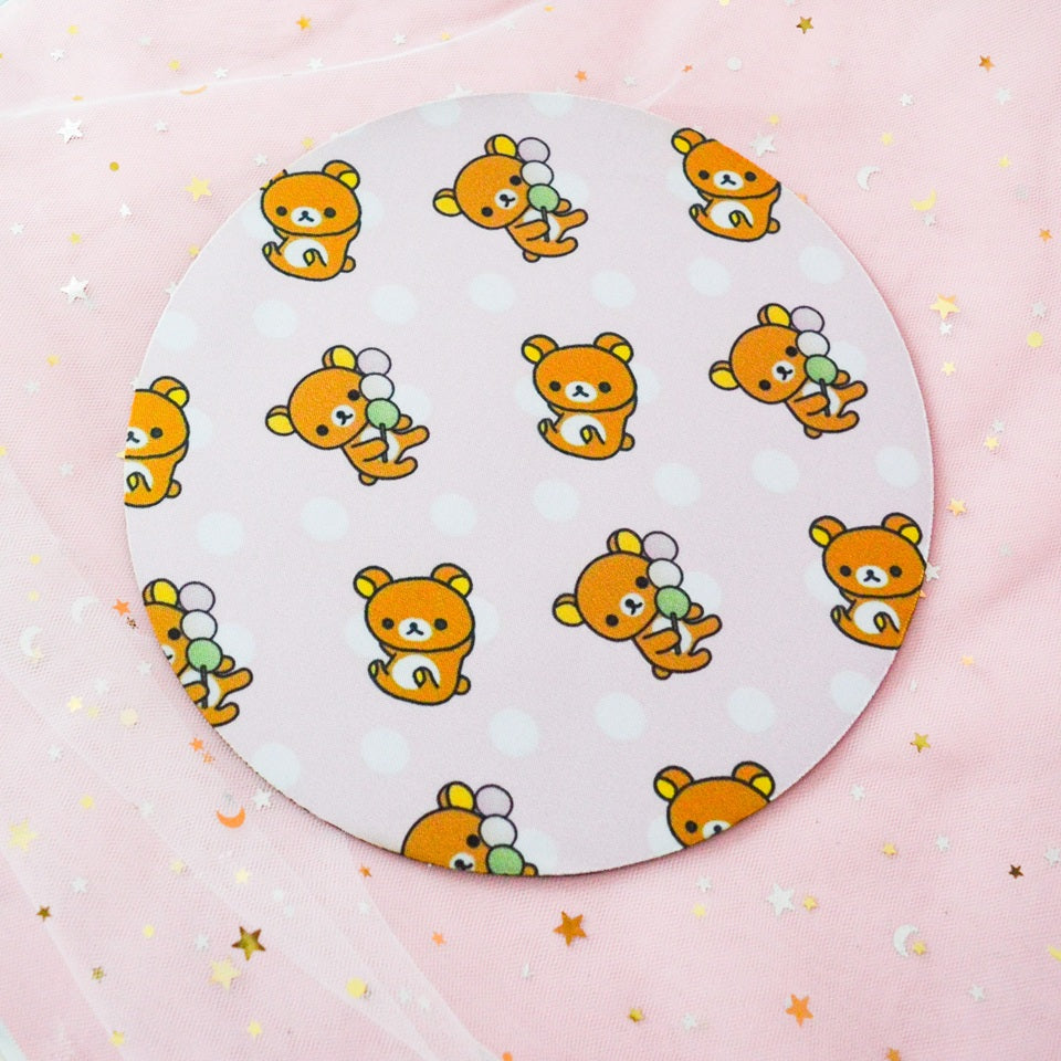 un tapis de souris rond au motif de rilakkuma dégustant de délicieux dango. Couleurs vives et pastels.