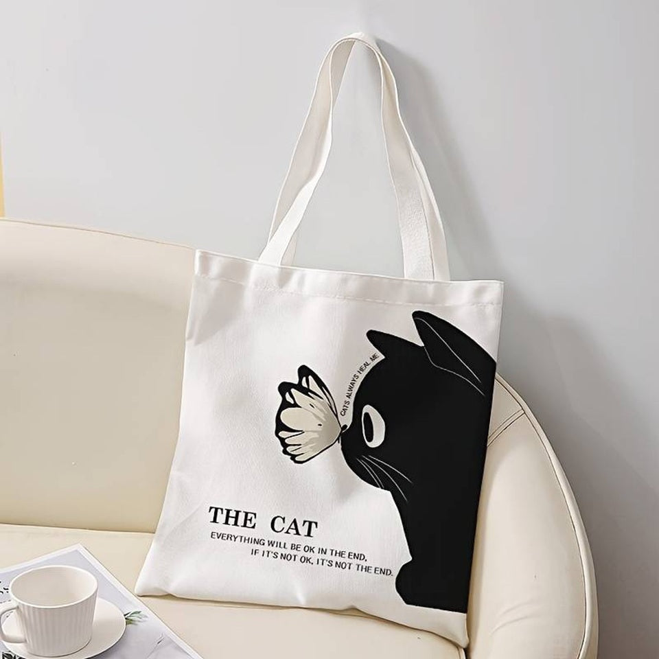 un tote bag léger et mignon en polyester représentant un adorable chat noir et un joli papillon posé sur sa truffe. L'ensemble est poétique et tendre.