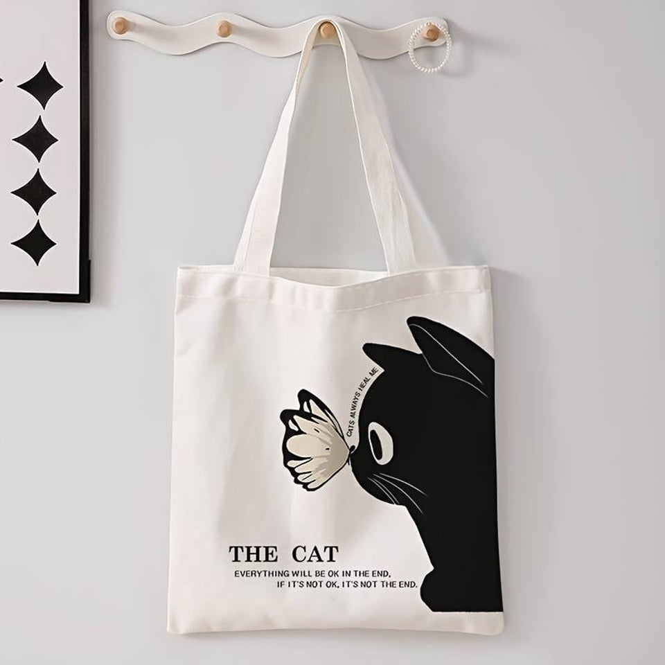 un tote bag léger et mignon en polyester représentant un adorable chat noir et un joli papillon posé sur sa truffe. L'ensemble est poétique et tendre.