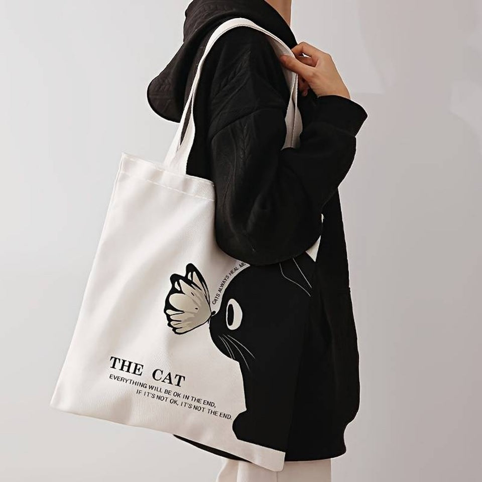 un tote bag léger et mignon en polyester représentant un adorable chat noir et un joli papillon posé sur sa truffe. L'ensemble est poétique et tendre.