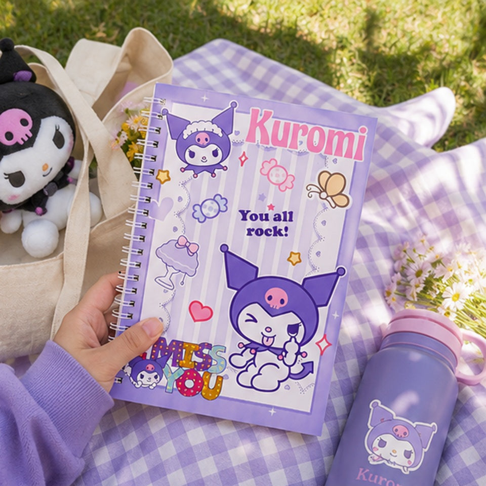 Main tenant un cahier à spirales Kuromi kawaii violet lors d’un pique-nique dans l’herbe ✨ Carnet adorable inspiré de l’univers Sanrio avec illustrations de Kuromi, bonbons et détails pastel, parfait pour écrire ses notes, son journal ou dessiner. Ambiance douce et cosy avec plaid à carreaux, fleurs et accessoires kawaii violets.