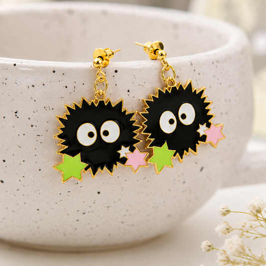 une paire de boucles d'oreilles en forme de noiraudes, ces petits êtres qui ressemblent à des boules de suie. Elles sont accompagnées de petites étoiles qui rappellent les sucreries dont elles raffolent.