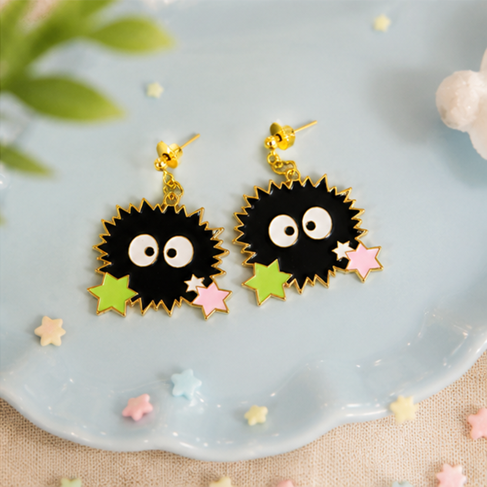 une paire de boucles d'oreilles en forme de noiraudes, ces petits êtres qui ressemblent à des boules de suie. Elles sont accompagnées de petites étoiles qui rappellent les sucreries dont elles raffolent.