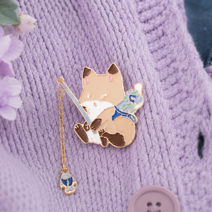 un pin's en forme de renard qui est en train de pêcher. Il a une canne à pêche composée d'une chainette. Au bout se trouve un poisson !