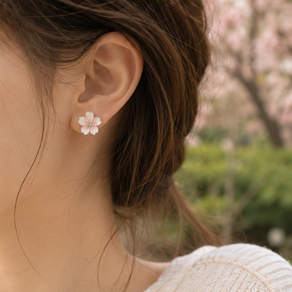 Une paire de puces d'oreilles argentées  délicates en forme de fleurs de cerisier dont le coeur est un petit strass brillant. Leur coloris rosé est délicate