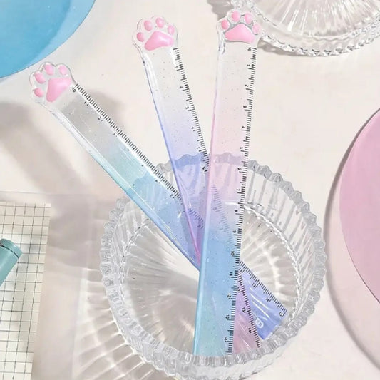 une règle pailletée en forme de patte de chat toute mignonne avec ses coussinets roses. graduée jusqu'à 15 cm, elle est trop kawaii avec son dégradé de couleur pastel