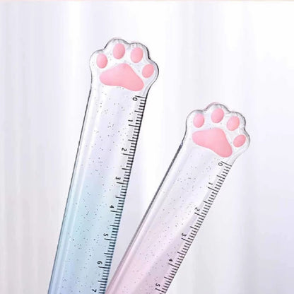 une règle pailletée en forme de patte de chat toute mignonne avec ses coussinets roses. graduée jusqu'à 15 cm, elle est trop kawaii avec son dégradé de couleur pastel