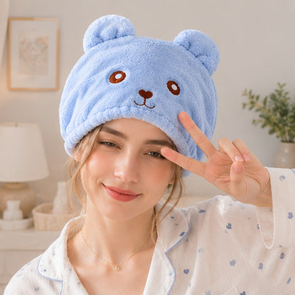 Personne portant une serviette pour cheveux kawaii bleue en forme d’ourson ultra douce et moelleuse ✨ Serviette adorable avec petites oreilles et visage brodé, parfaite pour sécher les cheveux après la douche tout en ajoutant une touche cute et cosy à sa routine beauté. Ambiance cocooning lumineuse avec pyjama pastel et décoration douce.
