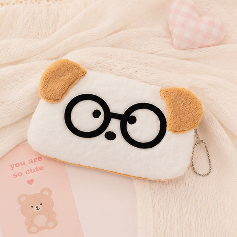 une adorable trousse toute douce en forme de chien blanc aux oreilles brunes. Il porte des lunettes noires rigolotes.