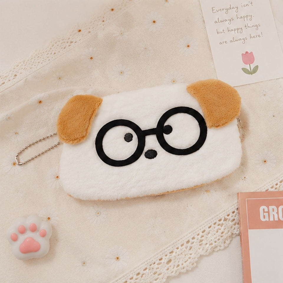 une adorable trousse toute douce en forme de chien blanc aux oreilles brunes. Il porte des lunettes noires rigolotes.