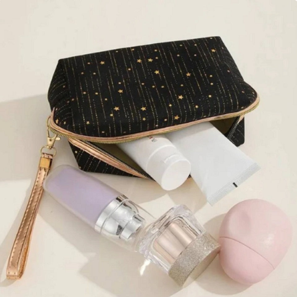 une trousse en velours noirs toute douce ornée de pluie d'étoiles dorées. LA fermeture éclair est dorée et elle possède une lanière de transport dorée.