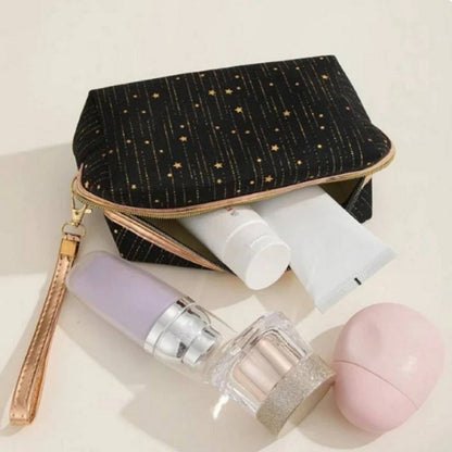 une trousse en velours noirs toute douce ornée de pluie d'étoiles dorées. LA fermeture éclair est dorée et elle possède une lanière de transport dorée.
