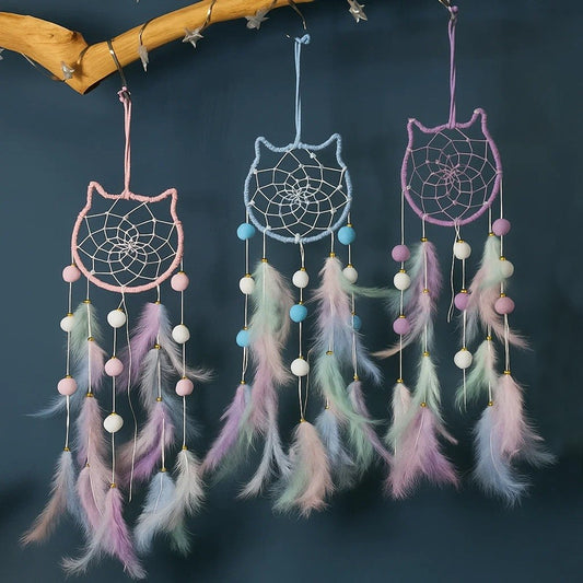 un superbe attrape-rêves en forme de tête de chat tout mignon. A l'intérieur, il y a des perles blanches dans le cordage. Des pompons et des plumes colorés y sont suspendus. L'ensemble est de couleur pastel dans un style poétique, bohême.