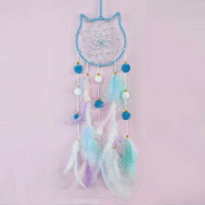 un superbe attrape-rêves en forme de tête de chat tout mignon. A l'intérieur, il y a des perles blanches dans le cordage. Des pompons et des plumes colorés y sont suspendus. L'ensemble est de couleur pastel dans un style poétique, bohême.