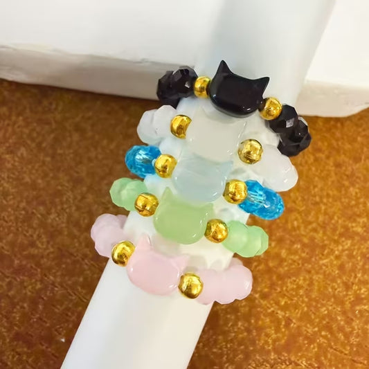 une bague taille élastique toute en parles et une breloque perles en forme de tête de chat. Disponible en coloris noir, blanc, bleu, vert, rose