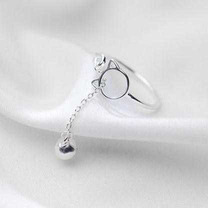 une bague argentée de taille réglable qui forme une tête de chat dans laquelle passe un petit grelot.