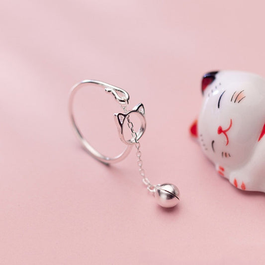 une bague argentée de taille réglable qui forme une tête de chat dans laquelle passe un petit grelot.
