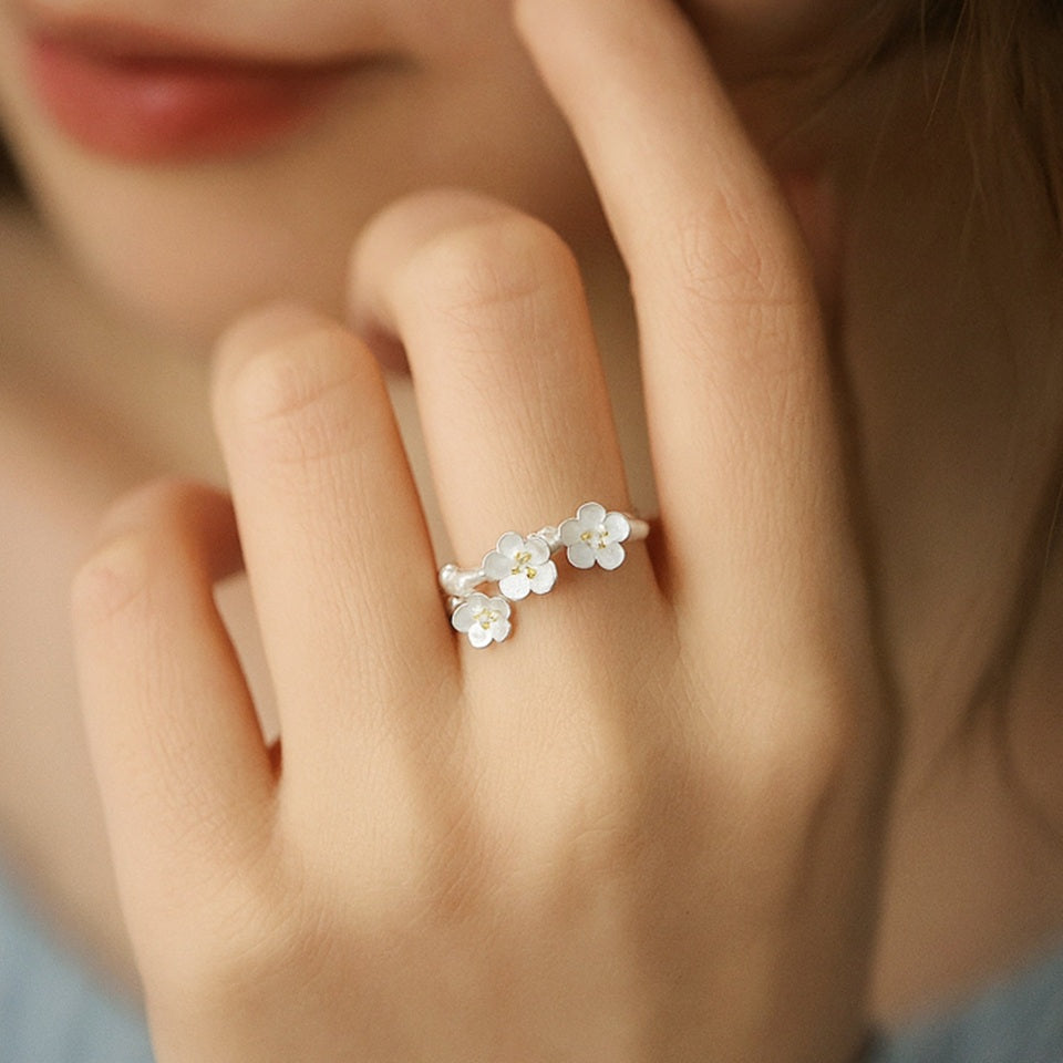 une bague en argent sterling 925 de taille réglable au design délicat de fleurs de pruniers. Les pistils sont dorés.