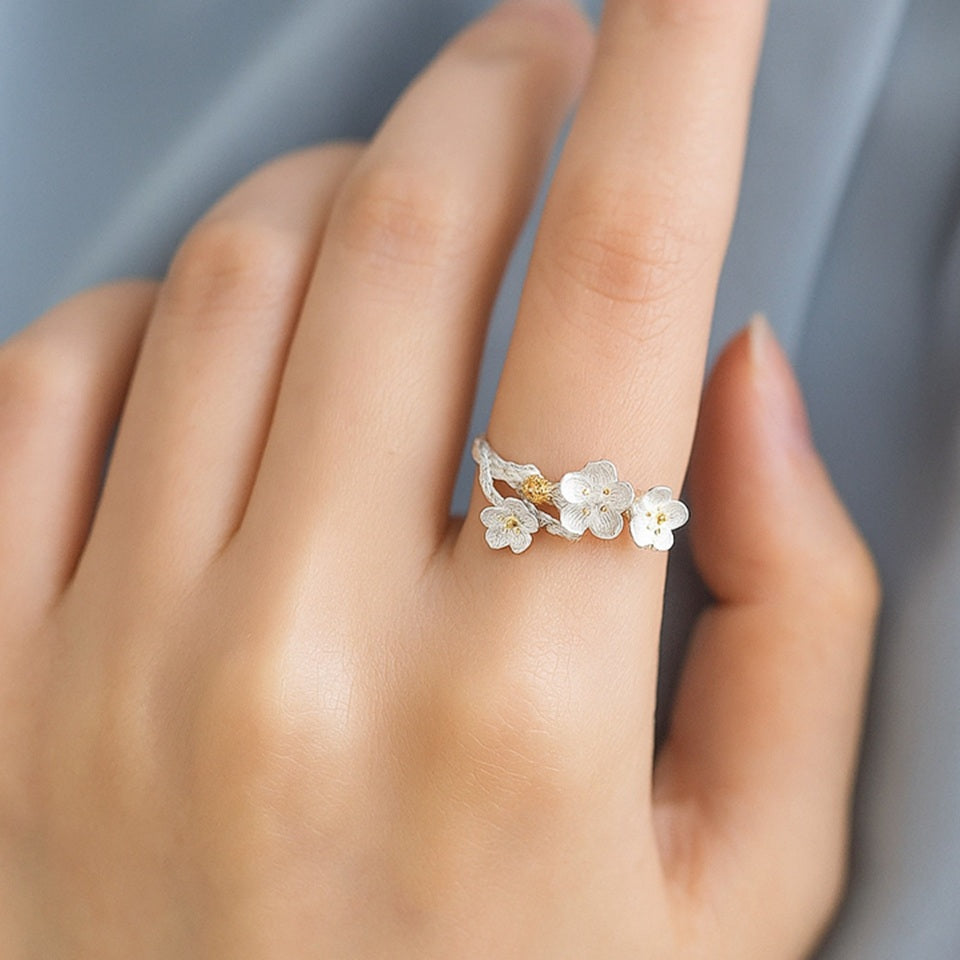 une bague en argent sterling 925 de taille réglable au design délicat de fleurs de pruniers. Les pistils sont dorés.