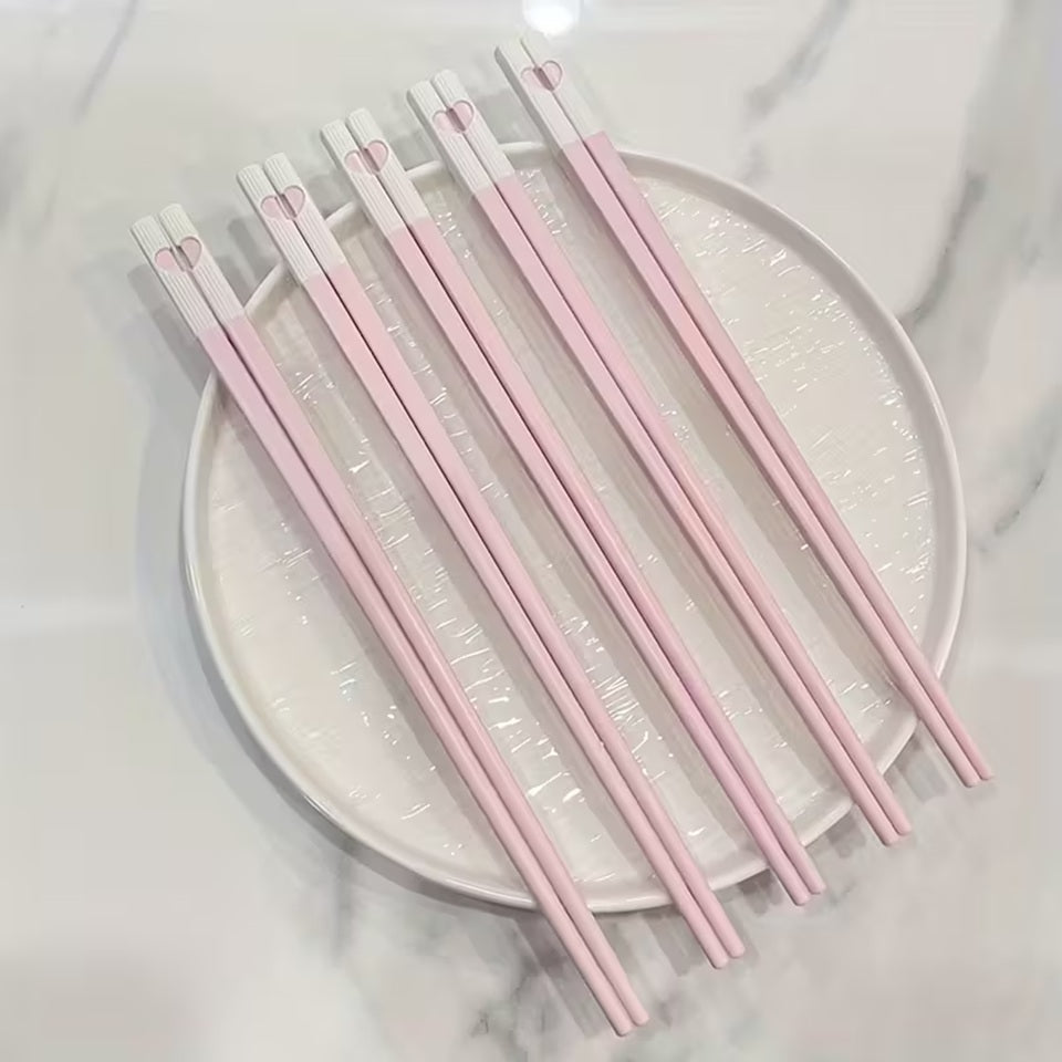 une jolie paire de baguettes roses et blanches. Au bout des baguettes, se trouve un petit coeur qui se reforme quand on regroupe les deux baguettes. C'est trop mignon !