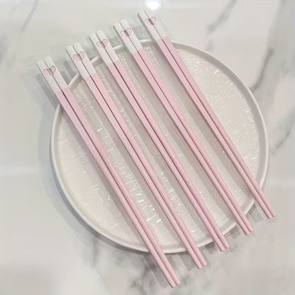 une jolie paire de baguettes roses et blanches. Au bout des baguettes, se trouve un petit coeur qui se reforme quand on regroupe les deux baguettes. C'est trop mignon !