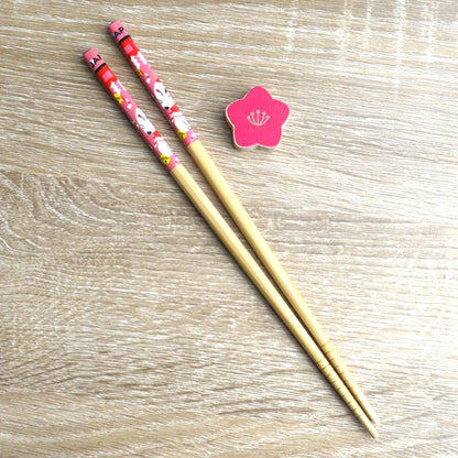 une paire de baguettes japonaises en bambou décoré d'un mignon kitsune et son repose baguette en forme de fleur de sakura rouge. Elégance et folklore japonais réunis pour une table élégante.