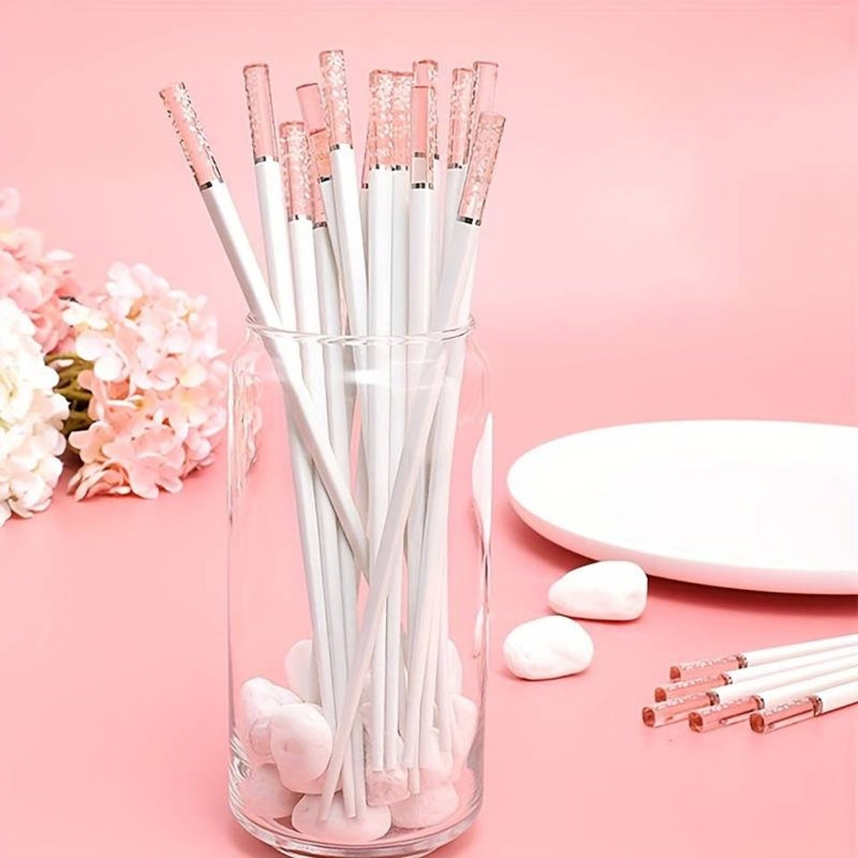 une paire de baguettes japonaises blanches délicatement décorées au bout de fleurs de sakura. Au bout, elles sont transparentes et joliment colorées de rose. Idéales pour une table élégante et raffinée.
