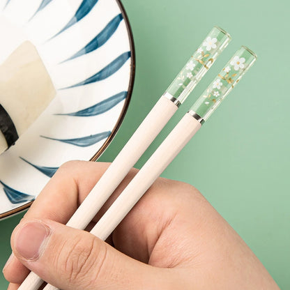 Une paire de baguettes japonaises élégantes au motif de fleurs de sakura. Le bout des baguettes est transparent et renferme des fleurs de sakura