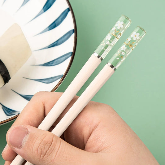 Une paire de baguettes japonaises élégantes au motif de fleurs de sakura. Le bout des baguettes est transparent et renferme des fleurs de sakura