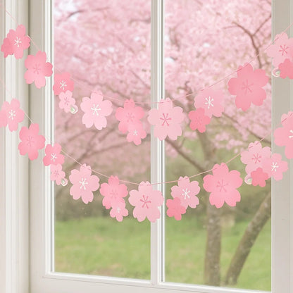 une banderole en papier formée de fleurs de sakura rose. A suspendre avec sa cordelette fournie. Elle ajoute une touche florale et mignonne à une pièce ou un extérieur.