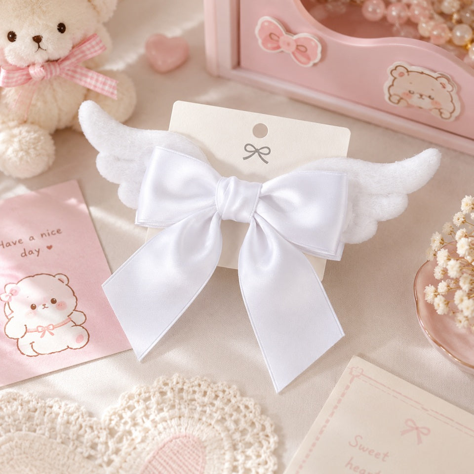 Barrette à cheveux blanche en forme de nœud avec ailes d'ange, présentée dans un décor kawaii aux tons pastel. Cet accessoire romantique et élégant apporte une touche poétique à toutes les coiffures et constitue une jolie idée cadeau pour les amateurs d'accessoires mignons.