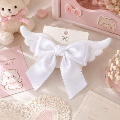 Barrette à cheveux blanche en forme de nœud avec ailes d'ange, présentée dans un décor kawaii aux tons pastel. Cet accessoire romantique et élégant apporte une touche poétique à toutes les coiffures et constitue une jolie idée cadeau pour les amateurs d'accessoires mignons.