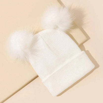 un bonnet blanc doté de deux adorables pompons blancs de chaque côté comme si c'était des oreilles