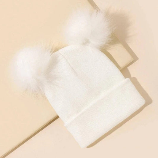 un bonnet blanc doté de deux adorables pompons blancs de chaque côté comme si c'était des oreilles