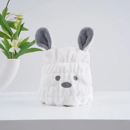 Un bonnet serviette pour cheveux kawaii blanc en forme de petit chien avec deux grandes oreilles, une bouille brodée et une texture douce et moelleuse. Un accessoire pratique et adorable pour un moment cocooning.