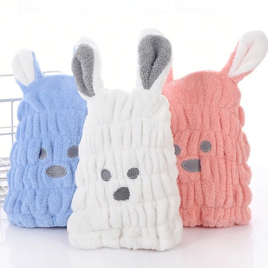 Trois bonnets serviette pour cheveux kawaii bleu, rose et blanc en forme de petit chien avec deux grandes oreilles, une bouille brodée et une texture douce et moelleuse. Un accessoire pratique et adorable pour un moment cocooning.