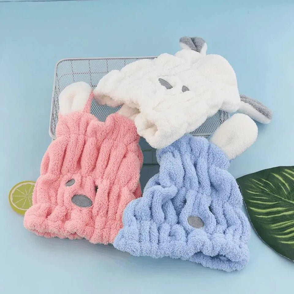 Trois bonnets serviette pour cheveux kawaii bleu, rose et blanc en forme de petit chien avec deux grandes oreilles, une bouille brodée et une texture douce et moelleuse. Un accessoire pratique et adorable pour un moment cocooning.