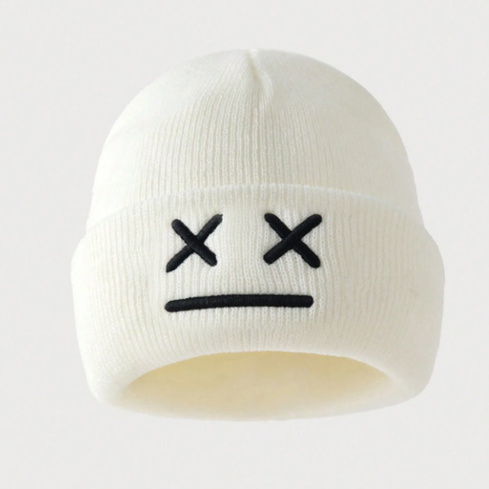 un bonnet à revers noir ou blanc brodé, représentant des yeux en forme de croix et une bouche minimaliste. Design tendance, moderne et minimaliste pour un look urbain street wear adorable.