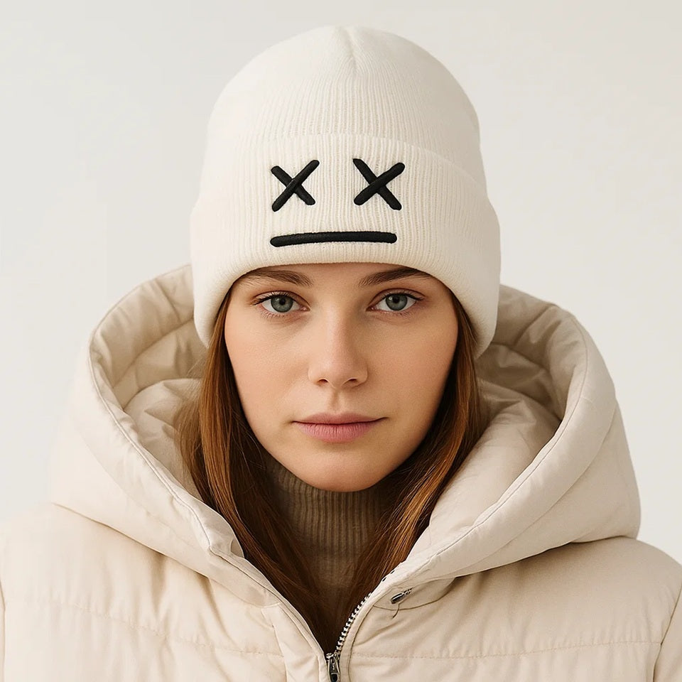 un bonnet à revers noir ou blanc brodé, représentant des yeux en forme de croix et une bouche minimaliste. Design tendance, moderne et minimaliste pour un look urbain street wear adorable.